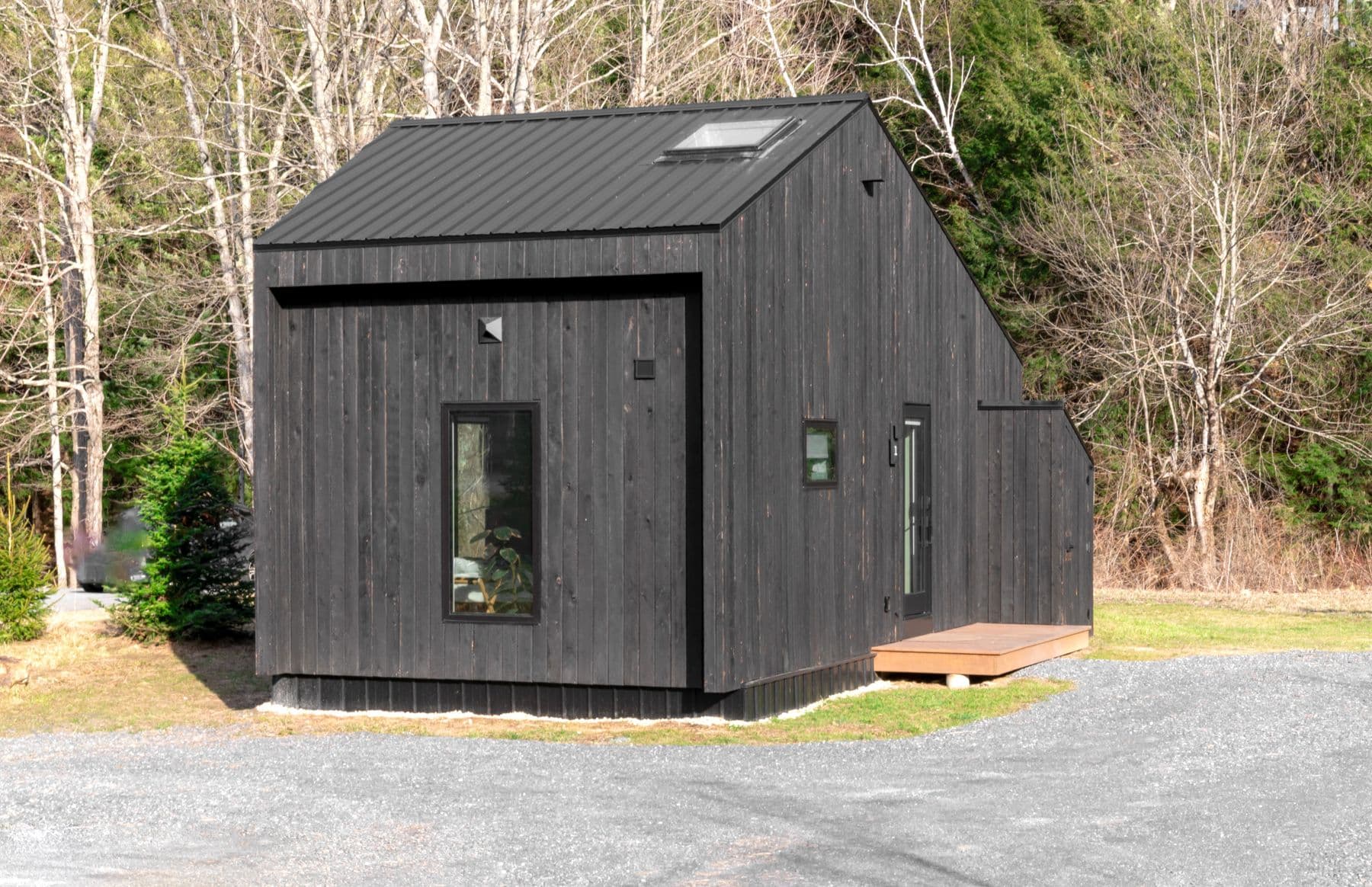 Modern black detached accessory dwelling unit among trees